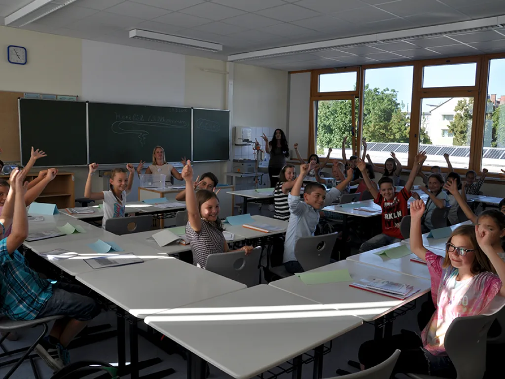 Mehrere Kinder melden sich im Unterricht.